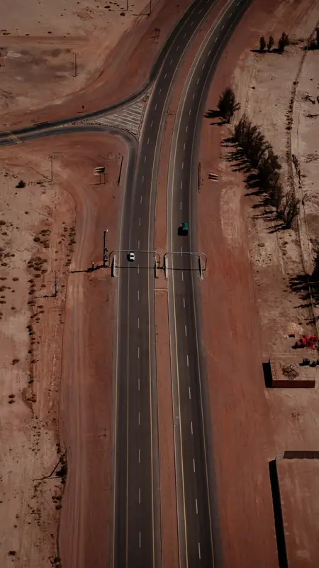 Highway cutting through red desert sand, seen from above