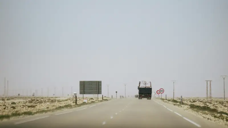 Truck on a desert highway approaching a road sign
