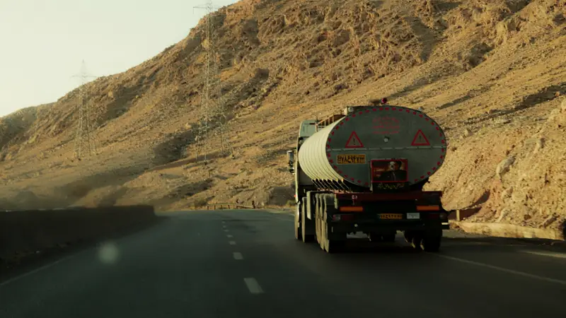 Tanker truck climbing a mountain road through rocky hills